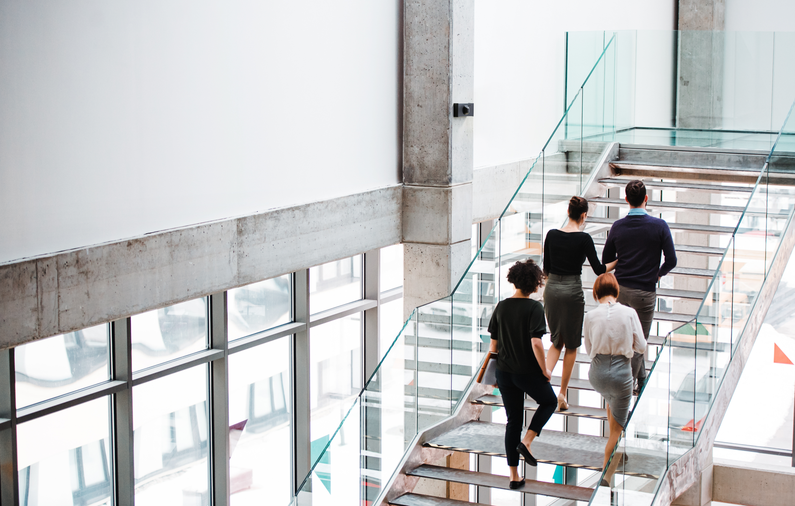 Four office workers walking up the stairs, passing weapon detection technology
